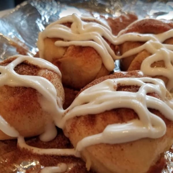 Close-up of several cinnamon rolls drizzled with white icing and sprinkled with cinnamon sugar.