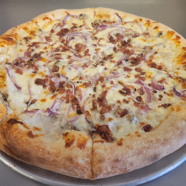 A whole Free Wheeler Pizza with white sauce, cheese, red onions, and crumbled sausage.