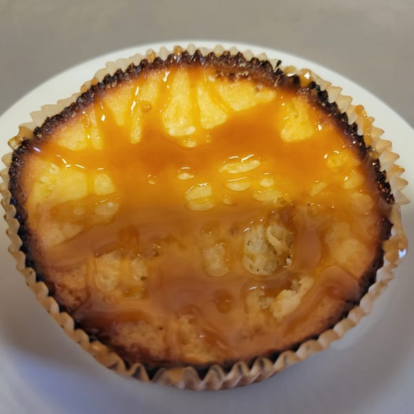 A close-up of a Free Wheeler Pizza dessert, a small cheesecake with caramel topping in a paper liner.